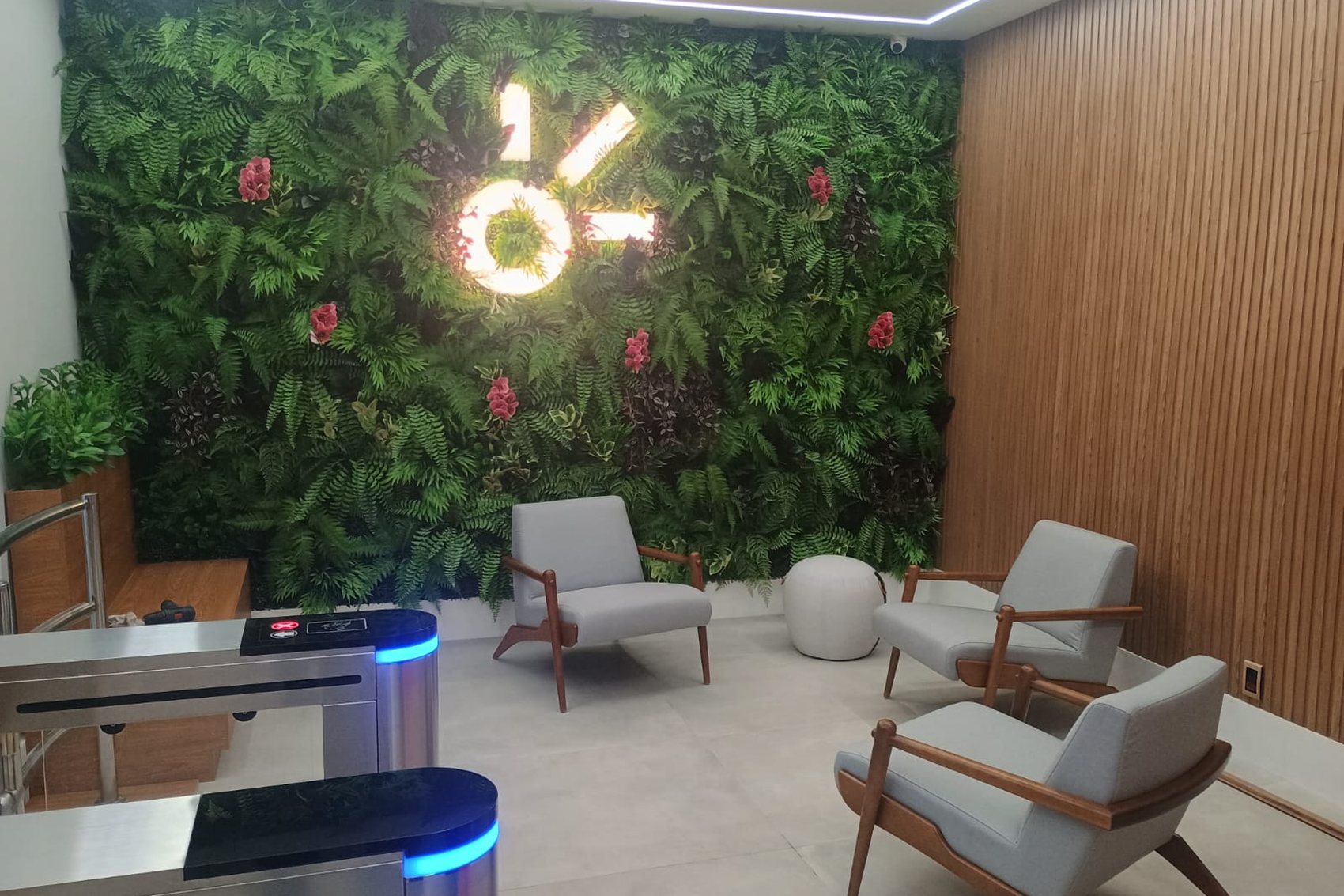ÁREA DE ESPERA — Parede verde com símbolo iluminado e lounge ao lado da recepção
